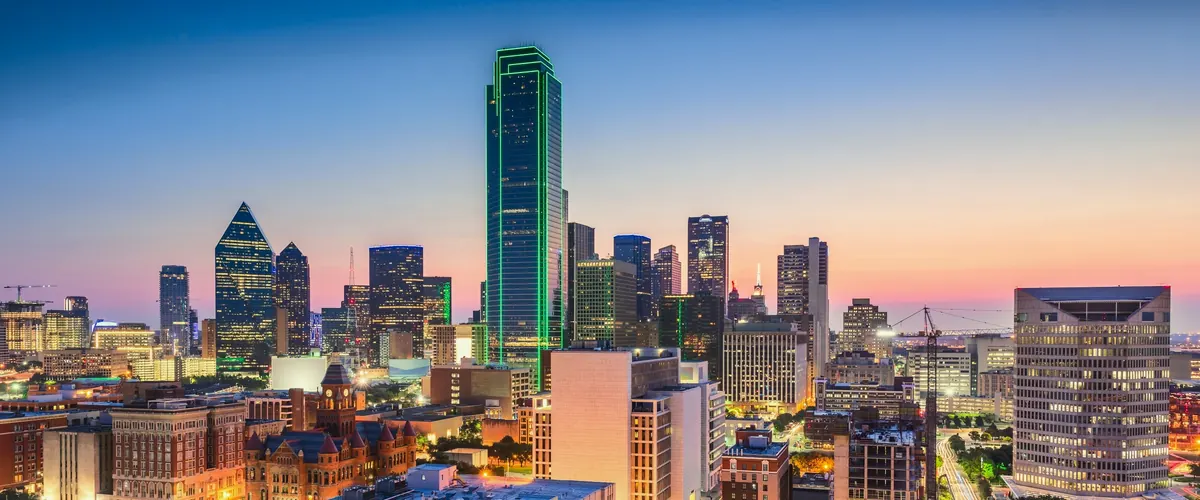 The Dallas skyline at dusk, with the city lights coming on