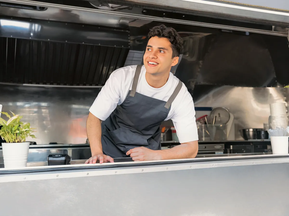 A man smiling from the counter of a food truck