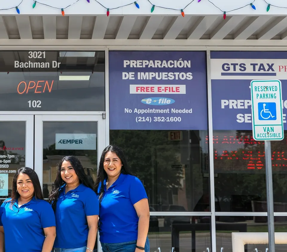 Three team members in blue shirts outside the office at 3021 Bachman Dr, under the Preparación de impuestos and GTS Tax Pro window signs